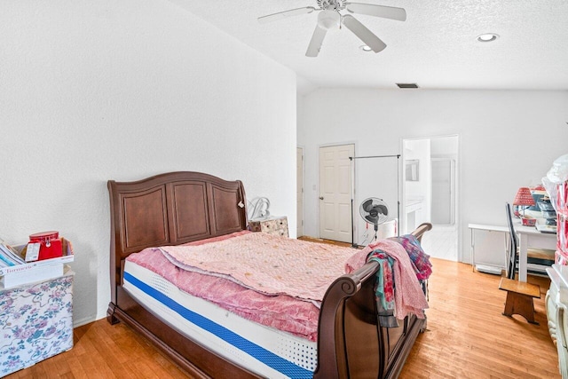 9023 Seminole Pratt Whitney Rd, The Acreage, FL 33470 - bedroom with lofted ceiling, light wood-style flooring, ceiling fan, ensuite bathroom, and a textured ceiling
