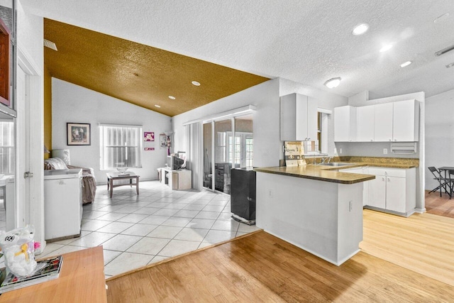 9023 Seminole Pratt Whitney Rd, The Acreage, FL 33470 - kitchen with lofted ceiling, a peninsula, white cabinetry, light wood finished floors, and a textured ceiling