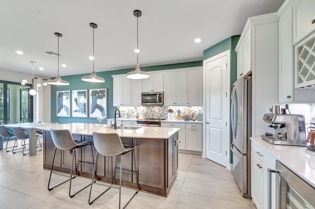 4646 Eventing St, Lake Worth, FL 33467 - kitchen with stainless steel appliances, wine cooler, backsplash, light tile patterned floors, and a breakfast bar
