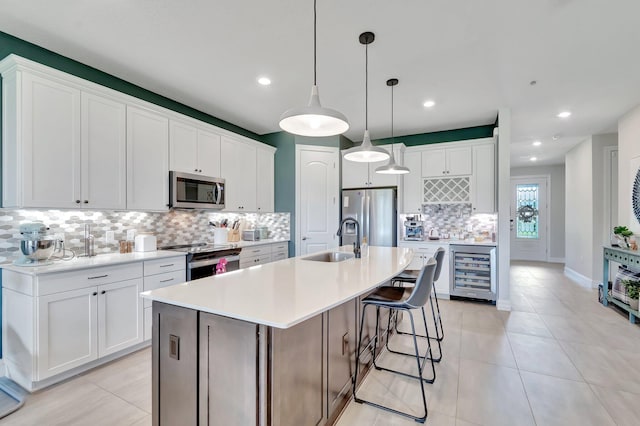 4646 Eventing St, Lake Worth, FL 33467 - kitchen featuring stainless steel appliances, beverage cooler, decorative backsplash, white cabinetry, and an island with sink