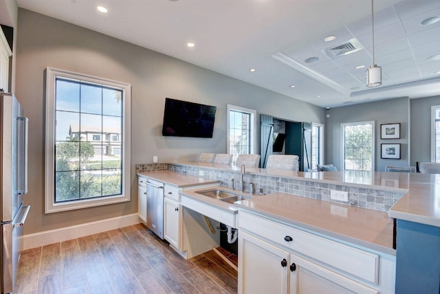 4646 Eventing St, Lake Worth, FL 33467 - kitchen with stainless steel appliances, wood finished floors, white cabinetry, light countertops, and hanging light fixtures