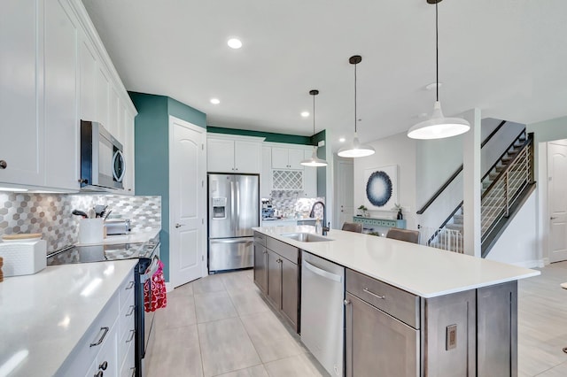 4646 Eventing St, Lake Worth, FL 33467 - kitchen with appliances with stainless steel finishes, backsplash, light countertops, a kitchen island with sink, and white cabinets