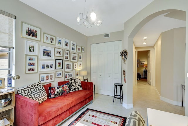 living room featuring light tile patterned floors, arched walkways, and baseboards