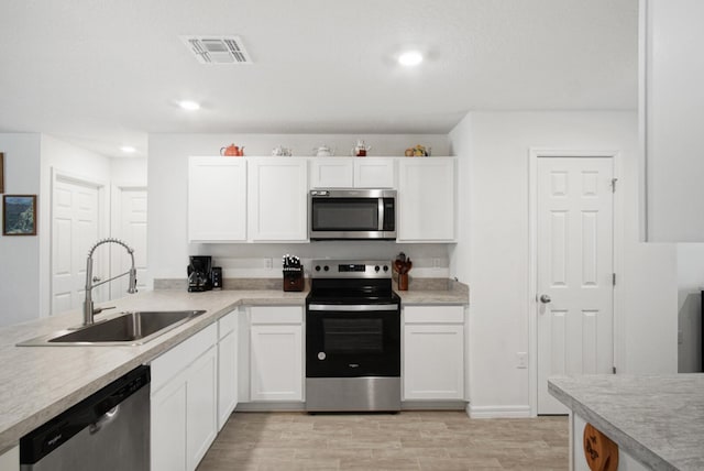 kitchen featuring stainless steel appliances, a sink, white cabinetry, light countertops, and recessed lighting