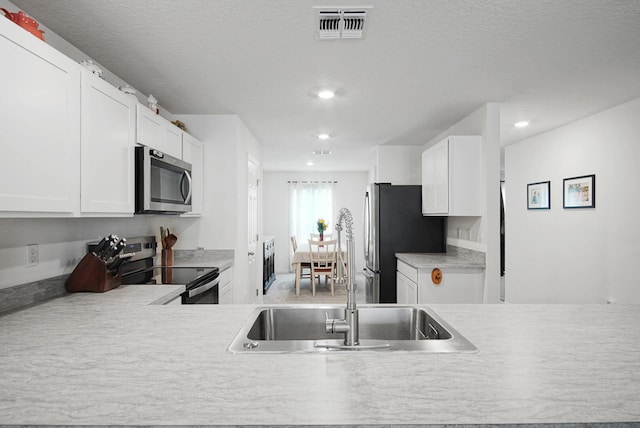 kitchen featuring stainless steel appliances, a sink, light countertops, white cabinets, and recessed lighting