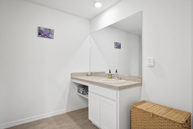 bathroom with wood finished floors, vanity, and baseboards