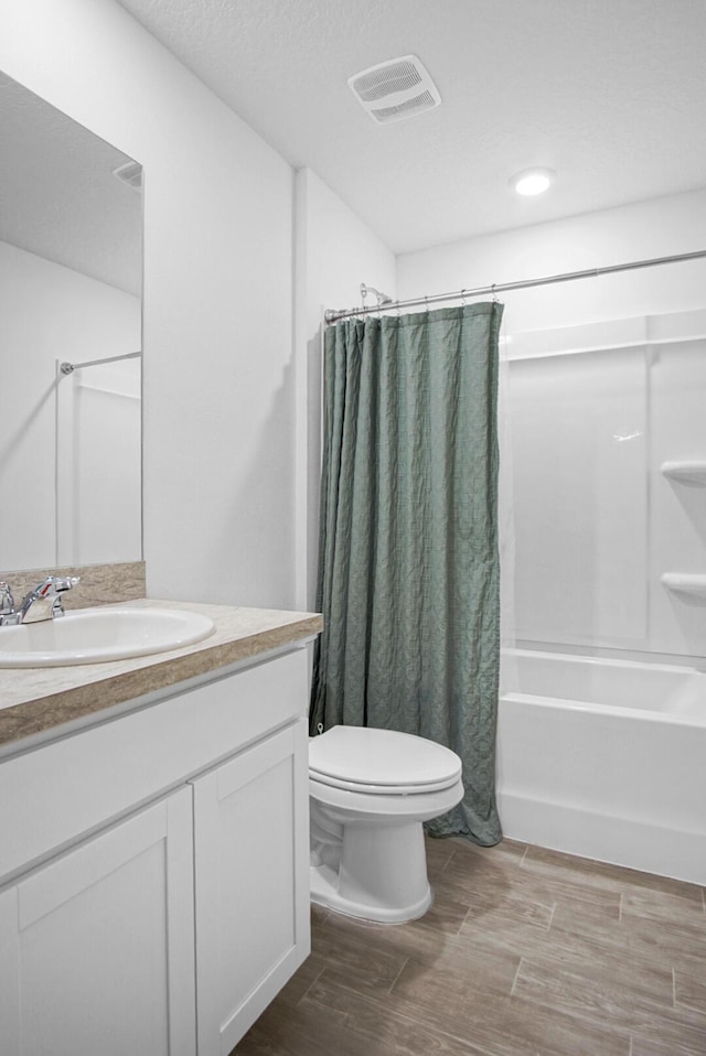bathroom with shower / bath combo with shower curtain, toilet, vanity, and wood finished floors