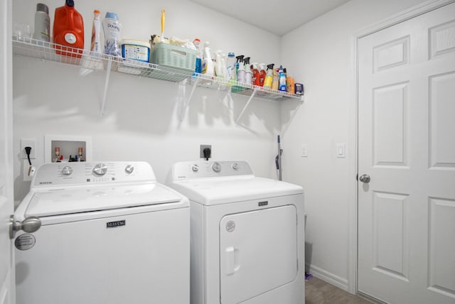 clothes washing area with washing machine and clothes dryer and baseboards