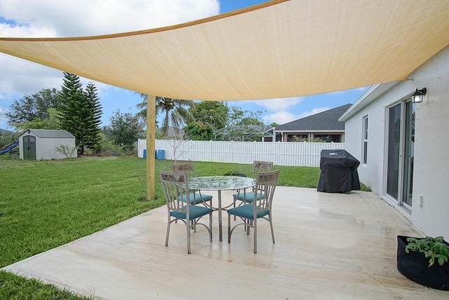 view of patio / terrace with a shed, outdoor dining space, an outbuilding, and grilling area