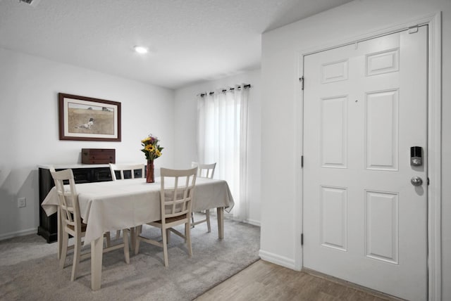 dining area with wood finished floors, baseboards, and a textured ceiling