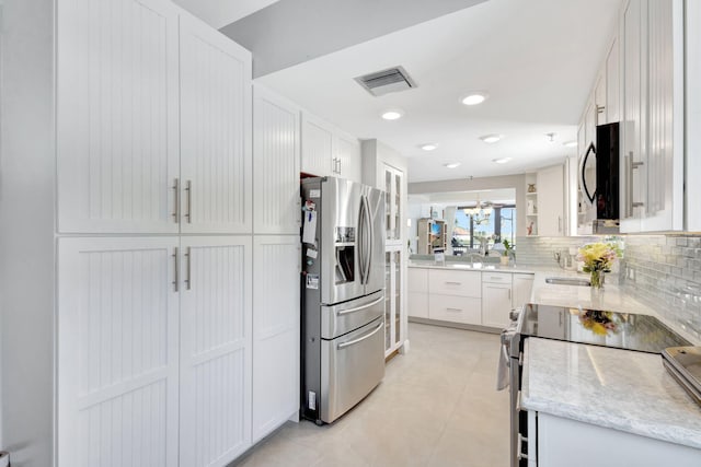 kitchen with appliances with stainless steel finishes, white cabinetry, tasteful backsplash, light stone countertops, and recessed lighting