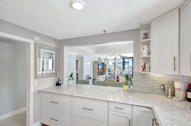 kitchen with a chandelier, open shelves, white cabinetry, backsplash, and baseboards