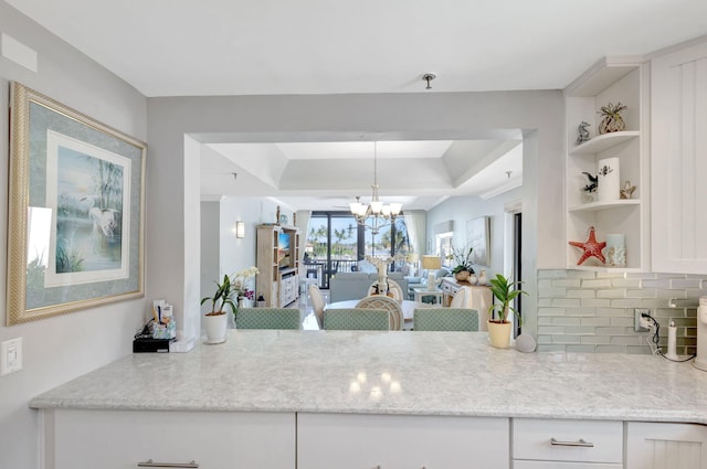 kitchen with open shelves, a chandelier, a raised ceiling, white cabinetry, and tasteful backsplash