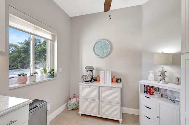kitchen featuring baseboards, light countertops, white cabinetry, and a ceiling fan