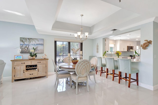 dining area with a raised ceiling, a chandelier, baseboards, ornamental molding, and light tile patterned floors