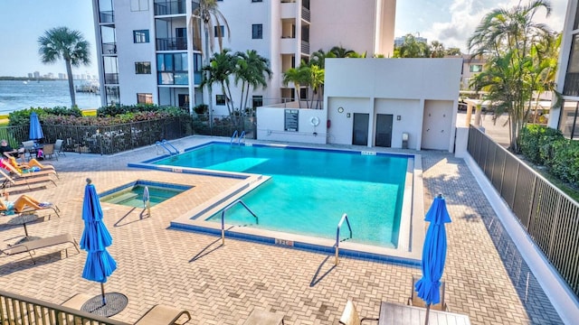 community pool with a community hot tub, a patio area, a fenced backyard, and a water view