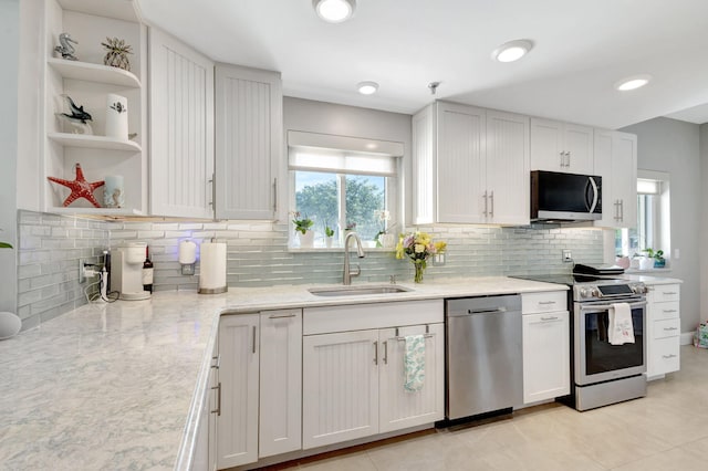 kitchen with stainless steel appliances, a sink, decorative backsplash, and light stone counters