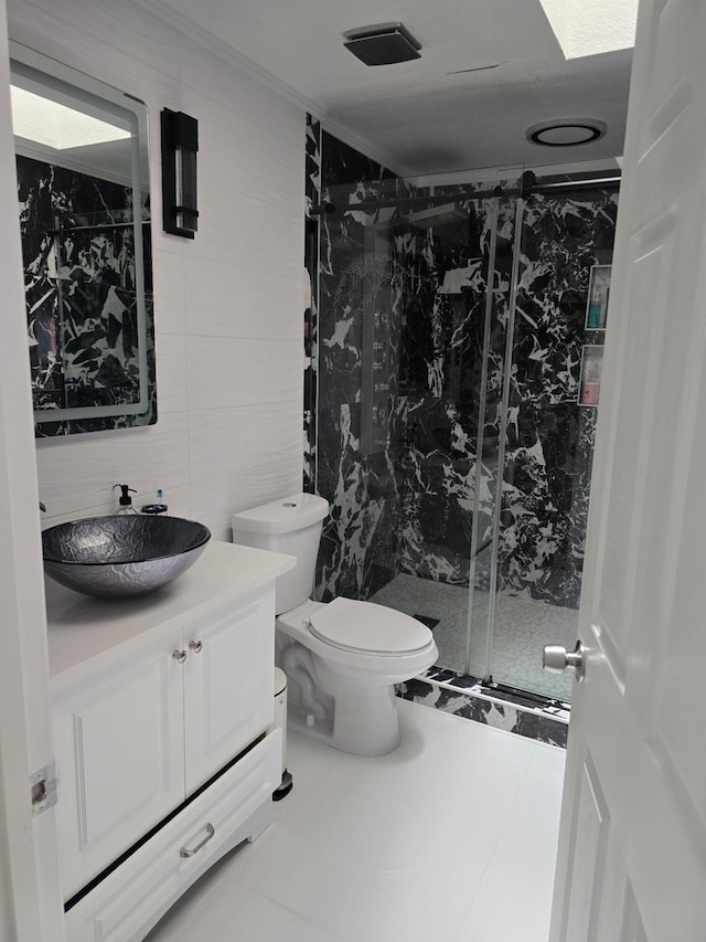 bathroom with tile walls, a marble finish shower, vanity, and toilet