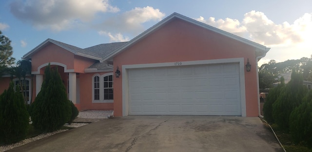ranch-style home featuring stucco siding, driveway, and a garage