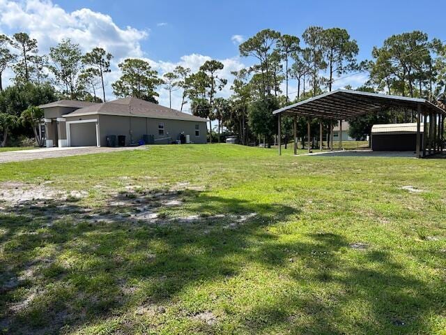 14413 71st Pl N, Loxahatchee, FL 33470 - view of grassy yard with an attached garage, gravel driveway, and a detached carport