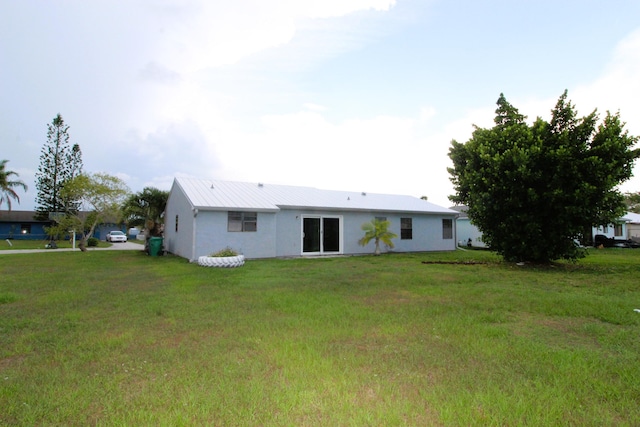 1561 SE Arenson Ln, Port Saint Lucie, FL 34952 - back of house featuring stucco siding, a lawn, and metal roof