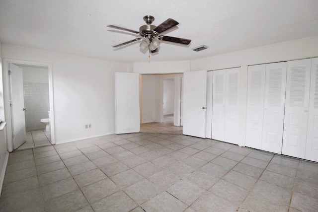 1561 SE Arenson Ln, Port Saint Lucie, FL 34952 - unfurnished bedroom with multiple closets, light tile patterned floors, ceiling fan, and ensuite bath