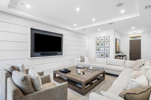 living area with recessed lighting, a raised ceiling, and light wood finished floors