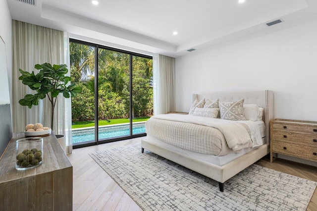bedroom featuring a tray ceiling, access to outside, recessed lighting, and light wood-style floors