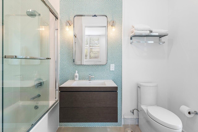 bathroom featuring toilet, shower / bath combination with glass door, and vanity