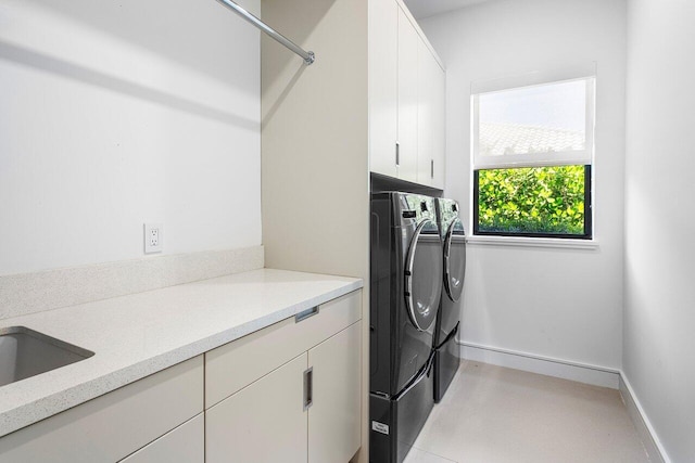 laundry room featuring independent washer and dryer, cabinet space, and baseboards