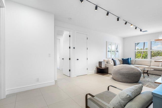 living area with baseboards, track lighting, and light tile patterned floors
