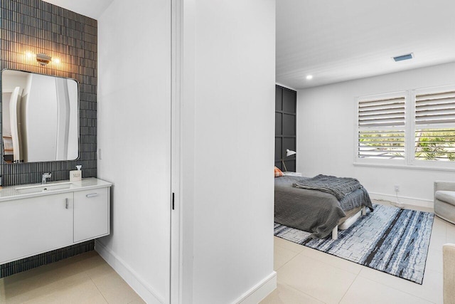 bedroom with a sink, baseboards, light tile patterned floors, and recessed lighting