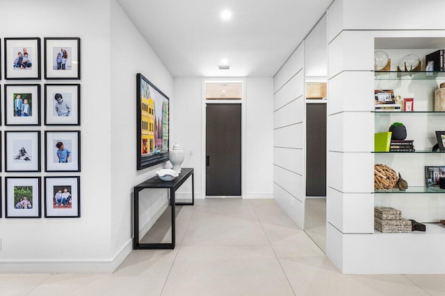 hall featuring baseboards and light tile patterned floors