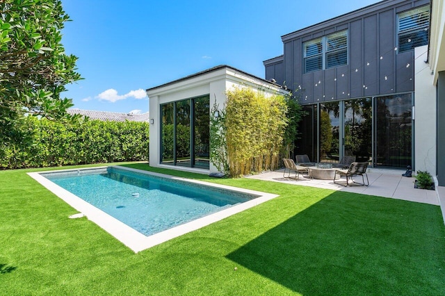 rear view of property featuring a patio, an outdoor fire pit, board and batten siding, and a yard