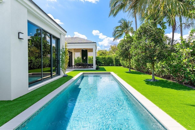swimming pool featuring a lawn and a patio area