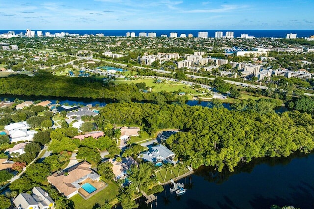 aerial view of property's location with a large body of water, nearby urban area, and a tree filled landscape