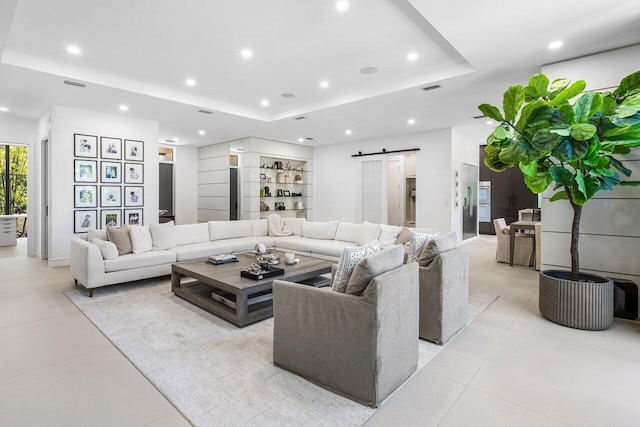 living area featuring a barn door, a raised ceiling, light tile patterned flooring, and recessed lighting