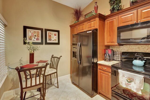 212 Cypress Point Dr, Palm Beach Gardens, FL 33418 - kitchen featuring black appliances, brown cabinetry, baseboards, light stone counters, and tasteful backsplash