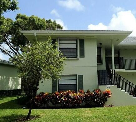 view of home's exterior featuring stucco siding, a lawn, and stairs