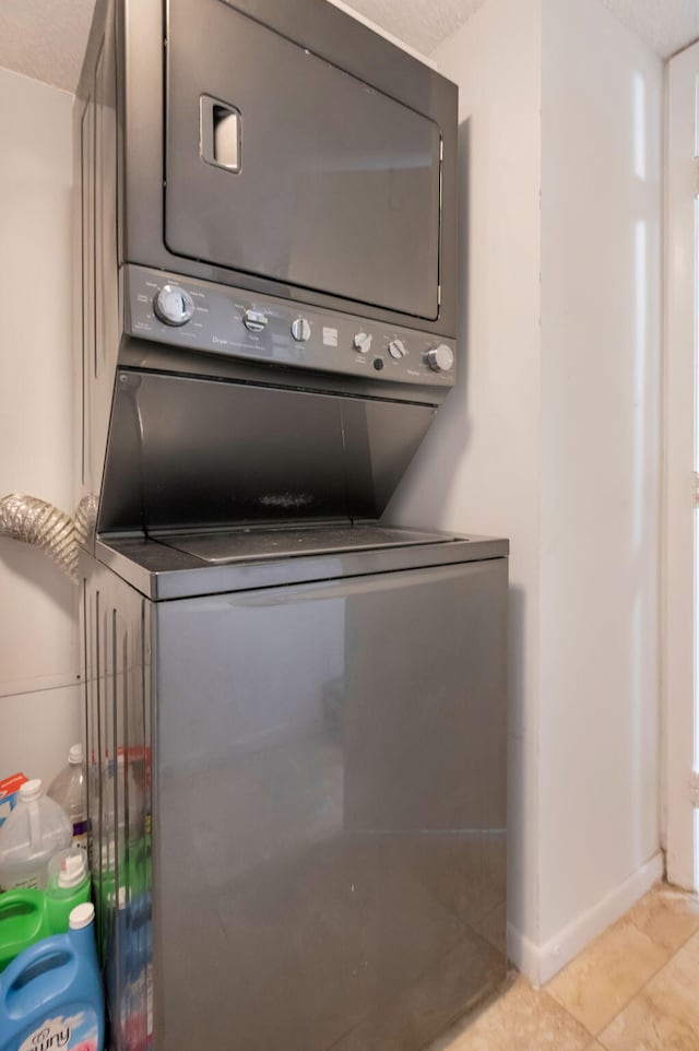 2070 Homewood Blvd Unit 1115, Delray Beach, FL 33445 - laundry room with stacked washing machine and dryer, baseboards, and light tile patterned flooring