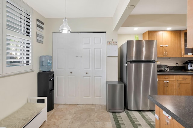 2070 Homewood Blvd Unit 1115, Delray Beach, FL 33445 - kitchen featuring freestanding refrigerator, dark countertops, brown cabinets, hanging light fixtures, and light tile patterned floors