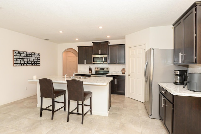 567 SW Paar Dr, Port Saint Lucie, FL 34953 - kitchen featuring appliances with stainless steel finishes, a sink, a kitchen island with sink, dark brown cabinetry, and recessed lighting
