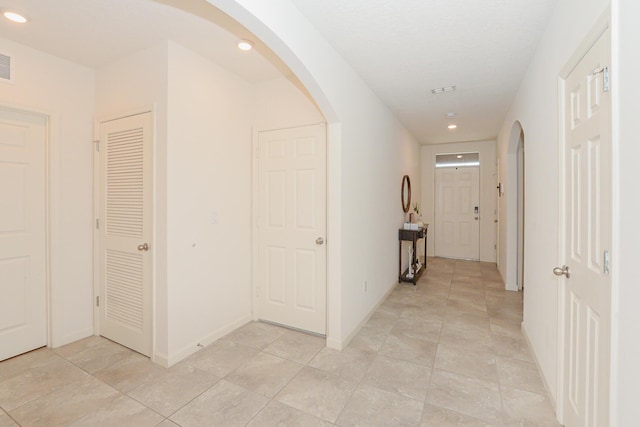 567 SW Paar Dr, Port Saint Lucie, FL 34953 - hallway featuring arched walkways, recessed lighting, light tile patterned floors, and baseboards