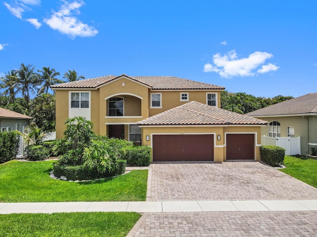 mediterranean / spanish-style house featuring stucco siding, an attached garage, a tiled roof, and driveway