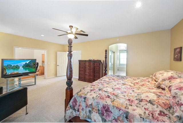 bedroom featuring arched walkways, light colored carpet, connected bathroom, recessed lighting, and a ceiling fan