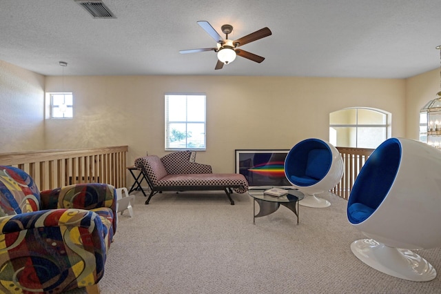living area featuring carpet, ceiling fan, and a textured ceiling