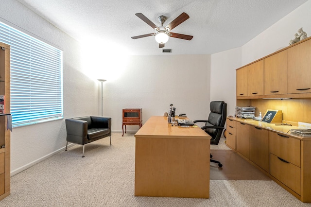 office area featuring ceiling fan, light carpet, a textured ceiling, a textured wall, and baseboards
