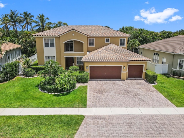mediterranean / spanish house featuring stucco siding, a tile roof, driveway, and an attached garage