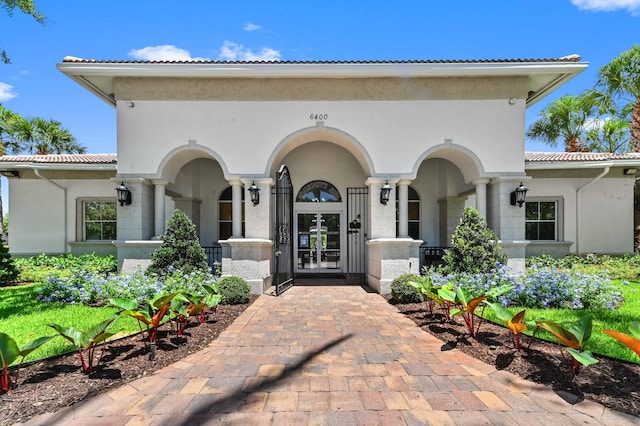 view of exterior entry with french doors, stucco siding, and a tile roof