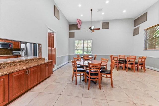 dining room featuring ceiling fan, light tile patterned floors, recessed lighting, a high ceiling, and baseboards